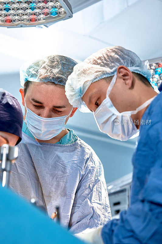 Group of surgeons doing surgery in hospital operating theater, international medical team doing critical operation
